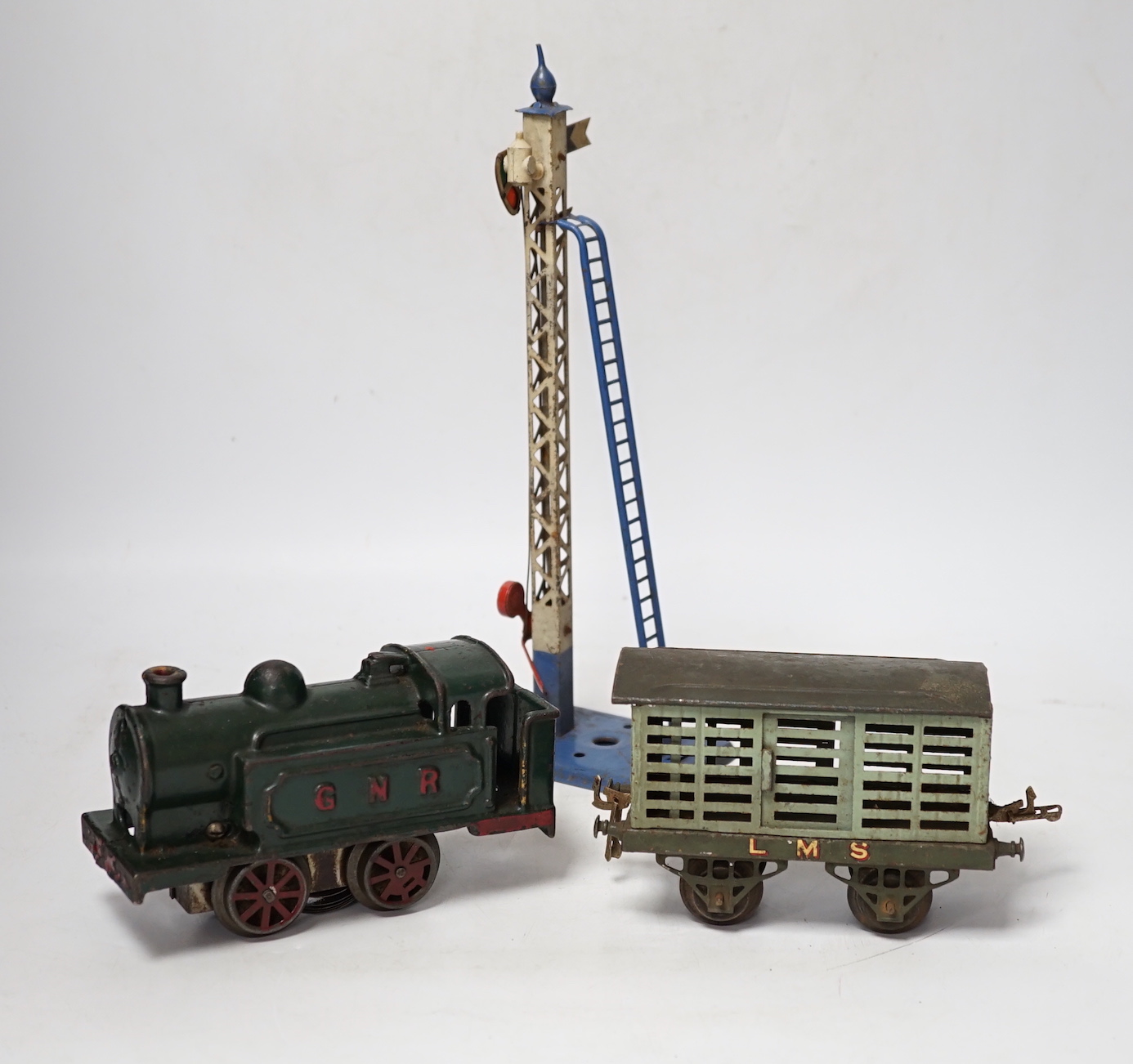 A collection of O gauge clockwork tinplate model railway, including a cast iron clockwork, GNR, 0-4-0T locomotive, six Hornby freight wagons, a small quantity of curved Bassett Lowke track sections and a few other items